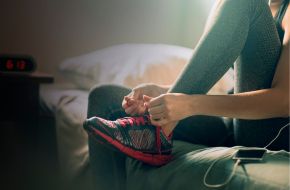 A young woman lacing up her trainer