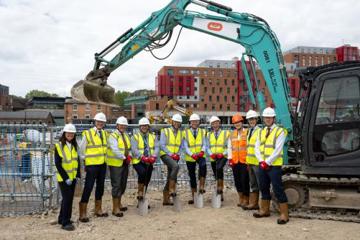 Oriel board with hard hats, high vis vests and spades breaking ground