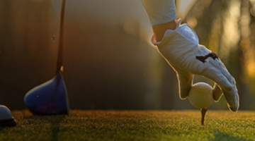 Hand of a person putting a golf ball on a tee