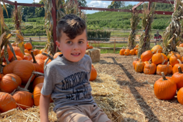 Young boy sitting on hay in a pumpkin patch