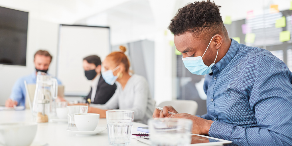 Medical person working at desk, wearing a mask