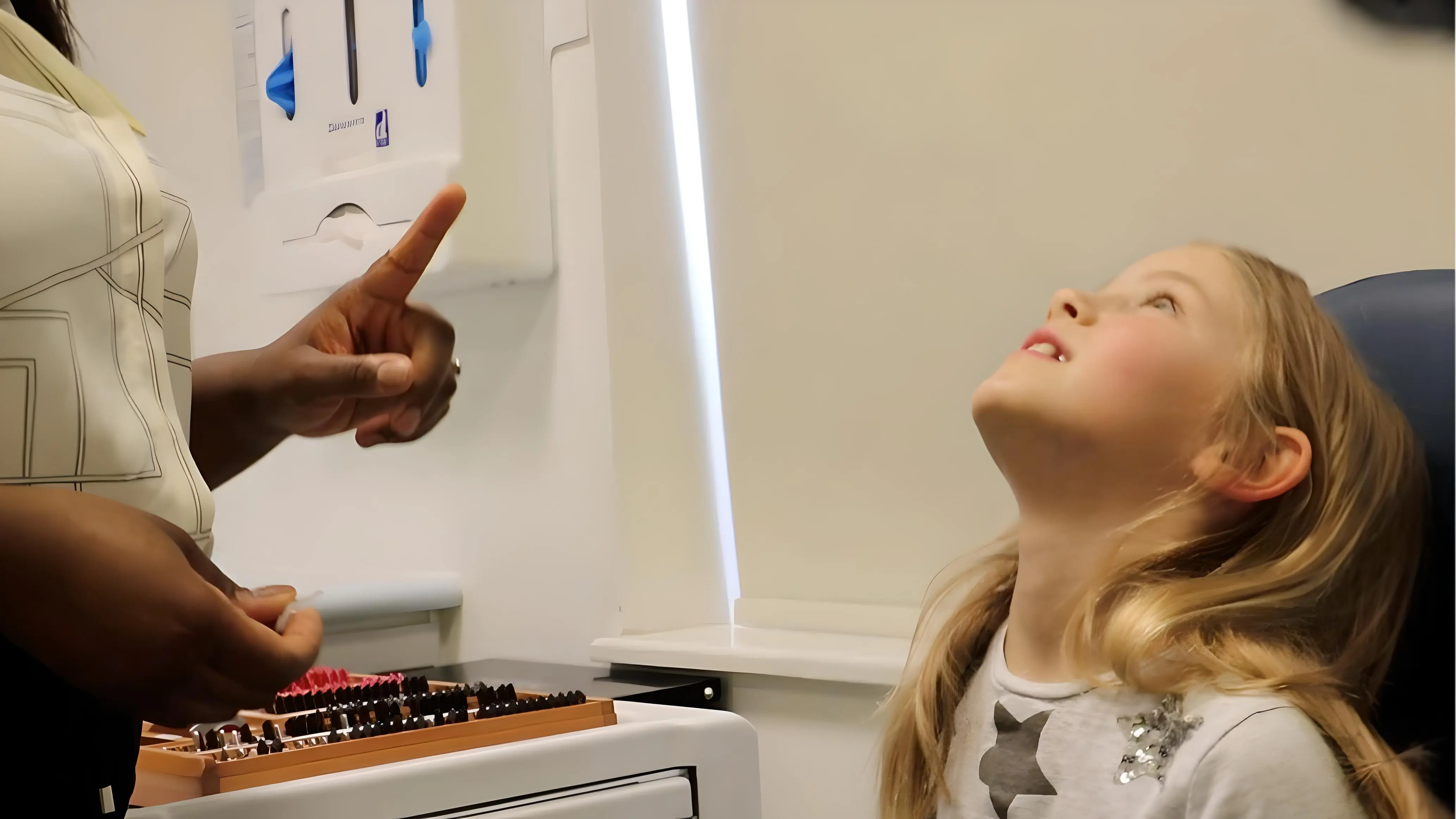 Child looking up as practitioner prepares to administer eye drops