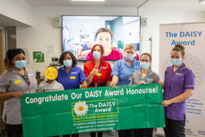 A small group of Moorfields nurses wearing face masks holding the Daisy Award banner