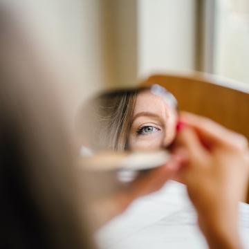 A mirror reflection of part of the woman's face and eye
