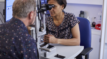 Patient being examined through slit lamp by Moorfields clinician.